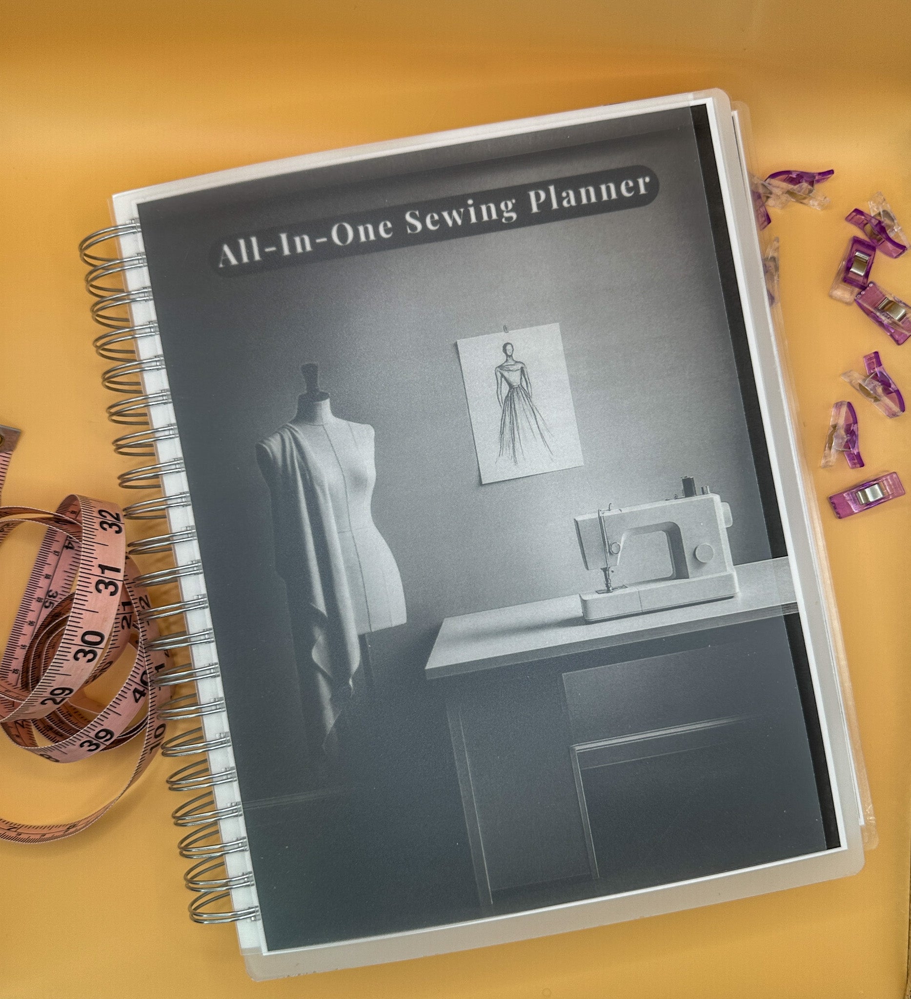 Sewing planner with sewing machine and mannequin on cover, surrounded by sewing tools