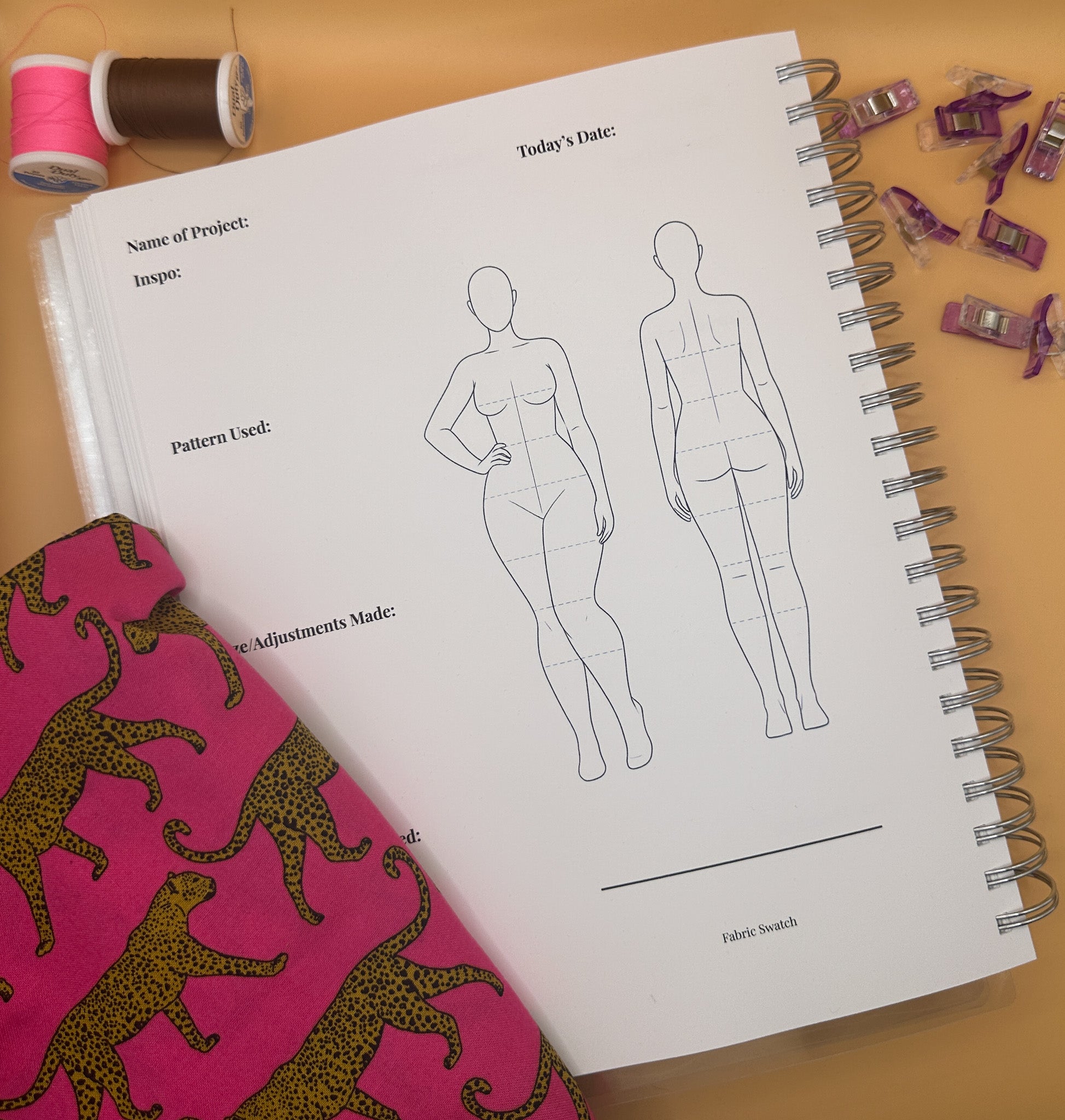 Spiral-bound notebook with fashion design templates with sewing materials.